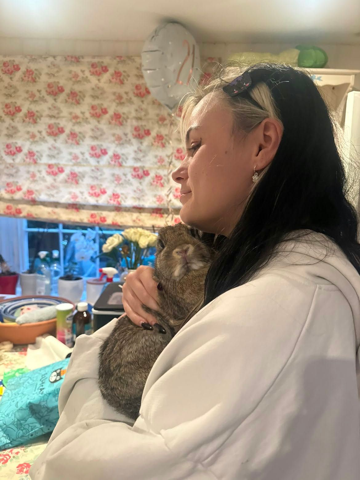 Jenny smiling as she cuddles a brown rabbit close against her shoulder
