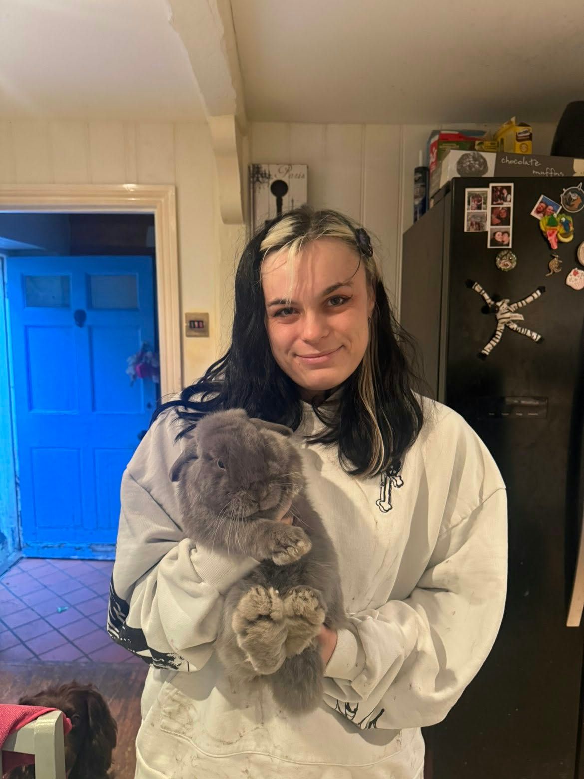 Jenny smiling at the camera while holding a fluffy grey lop-eared rabbit in her arms